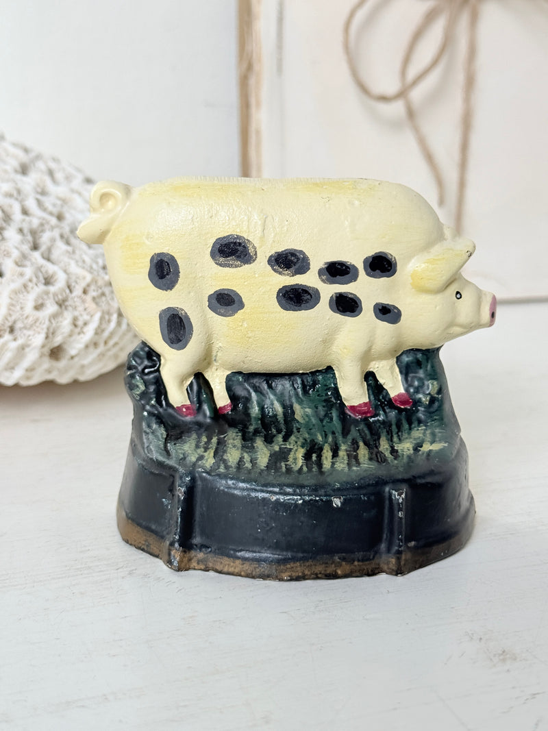 Vintage cast iron Old Spot pig doorstop in buttermilk with black spots walking through green grass