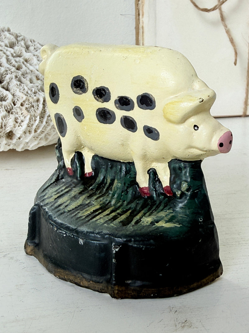 Close view of the spotted pig doorstop with pink snout, red trotters and streaked green grass