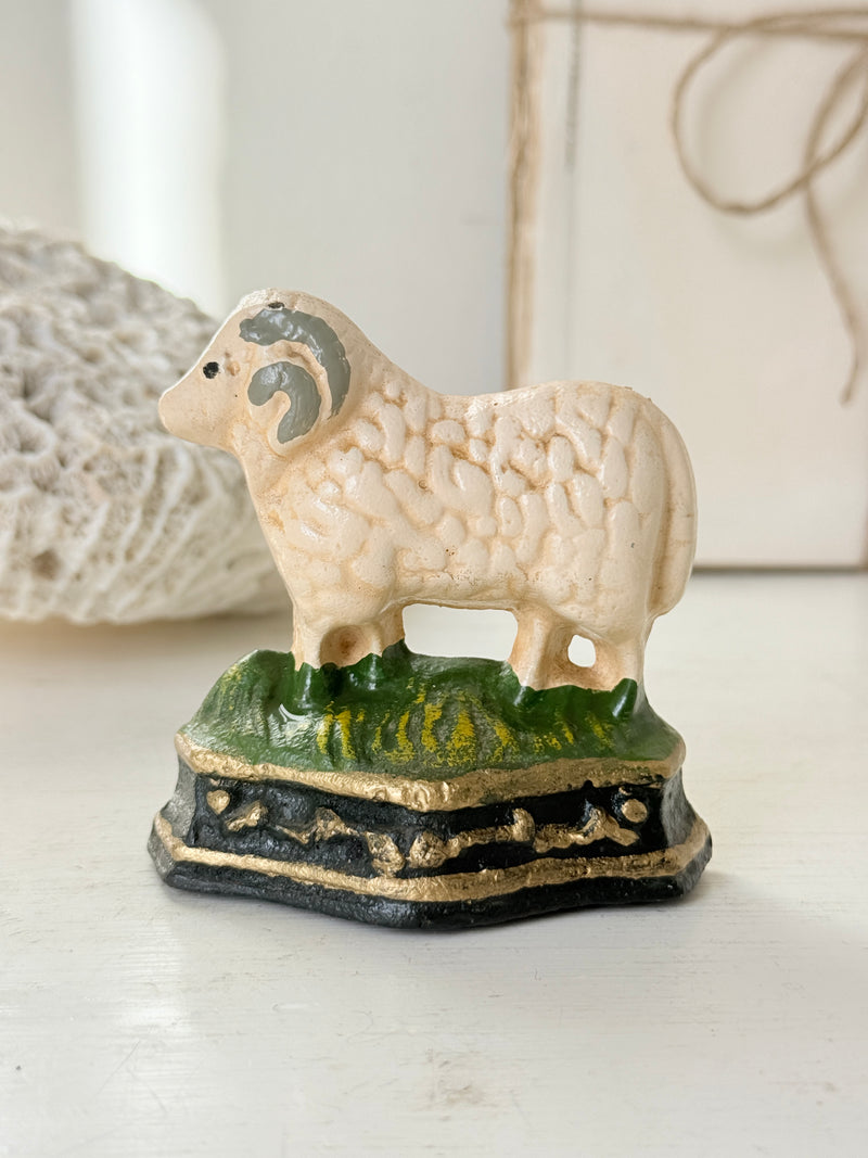 Side view of the cast iron sheep doorstop standing on bright green grass