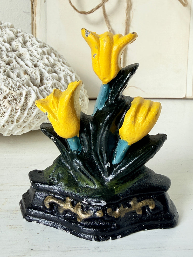 Vintage cast iron doorstop of three yellow tulips with dark green leaves on a black base with gold scrolls