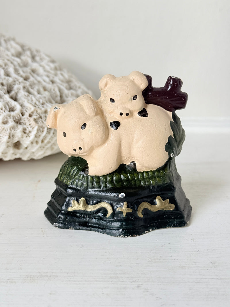 Front view of the two piglets cast iron doorstop on a white shelf